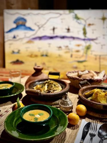 a table with plates of food and bowls of soup at Sahara Authentic Berber Camp in Mhamid