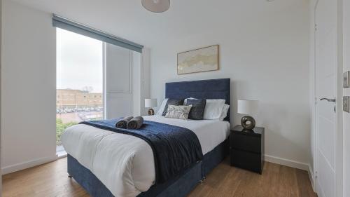 a bedroom with a large bed and a large window at 2-Bedroom Modern apt with Gym, roof terrace, Free Parking and 3 min walk to train st in Hersham