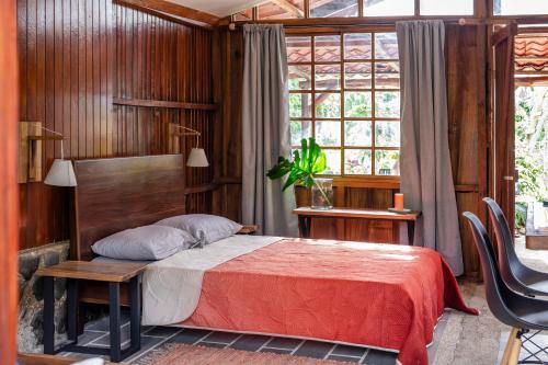 a bedroom with a bed and a table and a window at Casa Cúrcuma in Turrialba