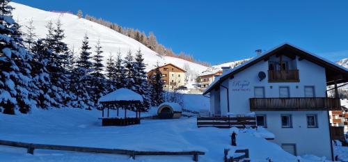 a building with a gazebo in the snow at Apartments Alpenroyal Arabba - Check-in at Garni Royal in Arabba