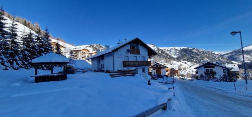 a building with snow on the ground next to a street at Apartments Alpenroyal Arabba - Check-in at Garni Royal in Arabba