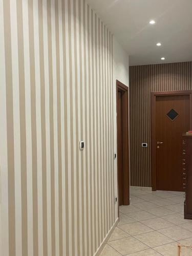 a hallway with a striped wall and a door at Pompei Duplex Apartment Deluxe in Boscoreale