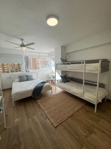 a bedroom with two bunk beds and a ceiling fan at Vacaciones en familia Ap Portitxol en Xàbia in Platja de l'Arenal