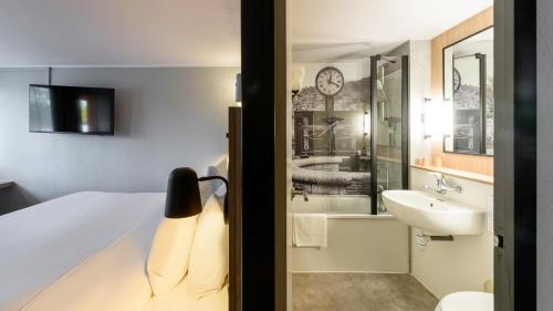 a hotel room with a bed and a sink at Campanile NATURE - Niort Est La Crèche in La Creche