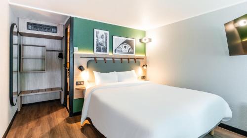 a bedroom with a white bed and a green wall at Campanile NATURE - Niort Est La Crèche in La Creche