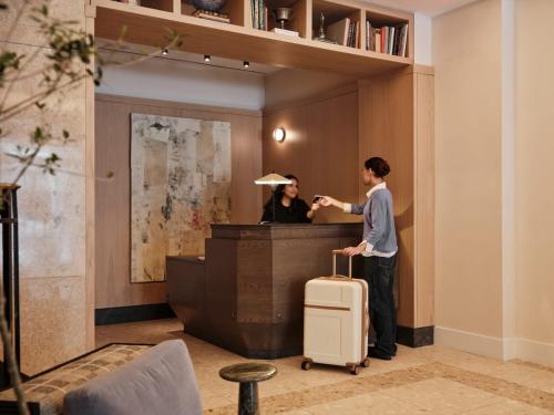 a man with a suitcase and a woman behind a desk at Mint House Washington Dc Downtown By Kasa in Washington, D.C.