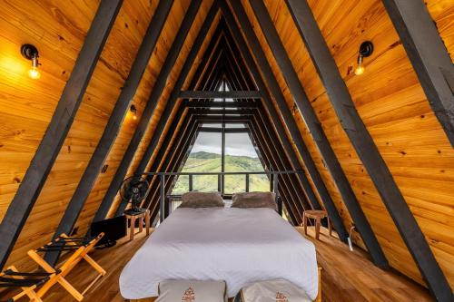 a bed in a room with a large window at Canda Cabana com SPA e vista para Cachoeiras in Baependi