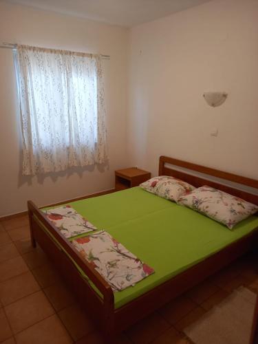 a bedroom with a green bed with a window at Apartmani Antonio Basina in Vrbanj