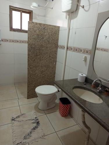 a bathroom with a toilet and a sink and a mirror at Kitnet simples in Capão da Canoa