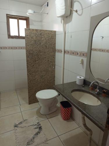 a bathroom with a toilet and a sink and a mirror at Kitnet simples in Capão da Canoa