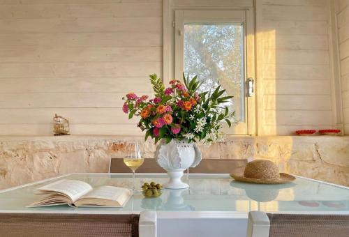 a table with a vase of flowers and a wine glass at Dimora Antonella - Ostuni 4 seasons - Splendid Villa Depandance with Private Swimming Pool in Ostuni