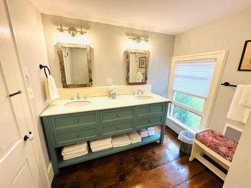 a bathroom with a green vanity with two sinks and a window at Mill Pond Inn in Jefferson