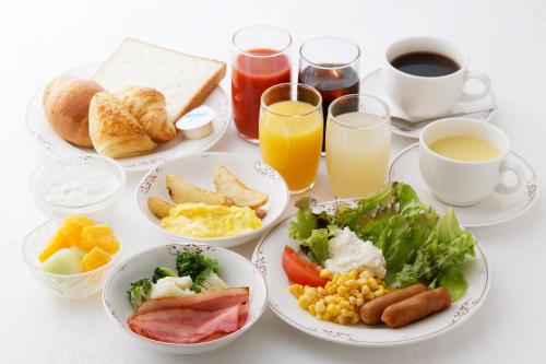 a table with plates of breakfast foods and drinks at Kumamoto Washington Hotel Plaza in Kumamoto