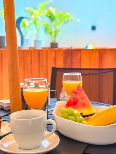a table with a bowl of fruit and two glasses of orange juice at Pousada Praia do Carioca Búzios in Búzios