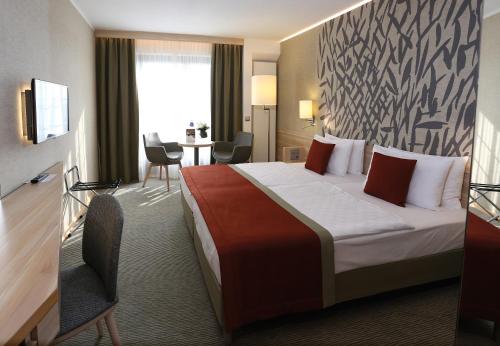 a hotel room with a large bed and a desk at Ensana Thermal Aqua in Hévíz