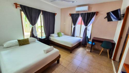 a room with two beds and a desk and a window at Hotel Monserrat in Mérida
