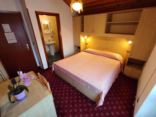 a small bedroom with a bed and a sink at Hotel Cime d'Auta in Falcade