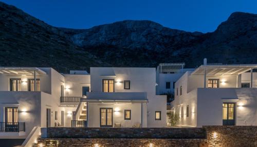 a white building at night with mountains in the background at Sifnos House - Rooms and SPA in Kamarai