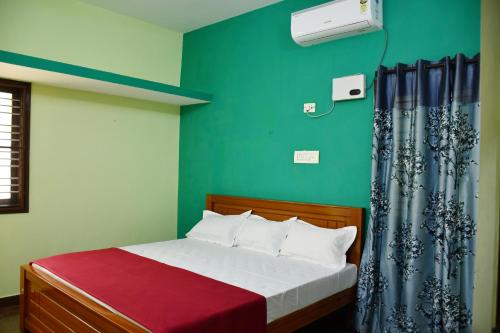 a bedroom with a bed and a green wall at Srinivasam service apartment in Madurai