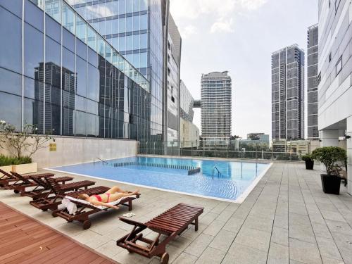 a pool on the roof of a building with lounge chairs at Cinnamon Life Residency in Colombo