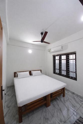 a white bed in a room with a ceiling fan at Enpathil Residency in Kollam