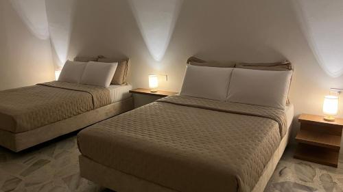 two beds in a hotel room with two lamps at Casa Celisa in Cali
