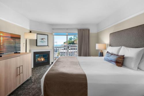 a hotel room with a large bed and a fireplace at Looking Glass Inn in Lincoln City