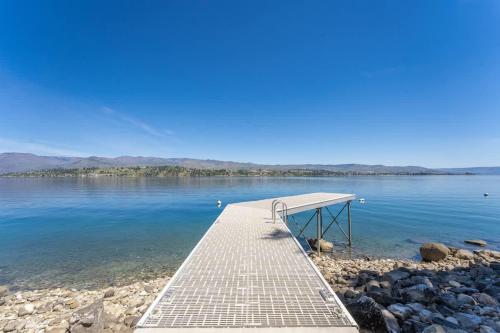 a dock on a body of water with mountains in the background at Constellations Lake House at Chelan - Pacific Retreats in Chelan