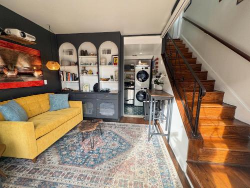 a living room with a yellow couch and a staircase at Capitol Hill Carriage House in Washington, D.C.