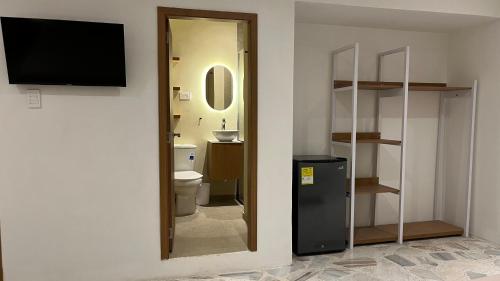 a bathroom with a toilet and a television on a wall at Casa Celisa in Cali