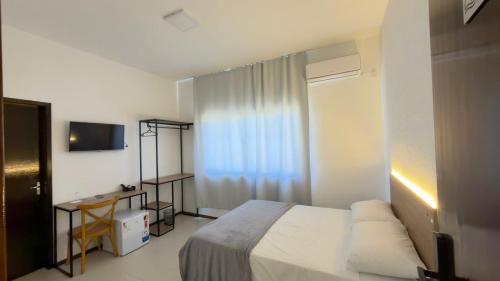 a bedroom with a bed and a desk and a television at Ibirama Vale Hotel in Ibirama