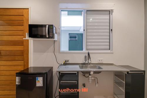 a kitchen with a sink and a microwave at Apartamento no tradicional Bairro do Bixiga em SP in São Paulo