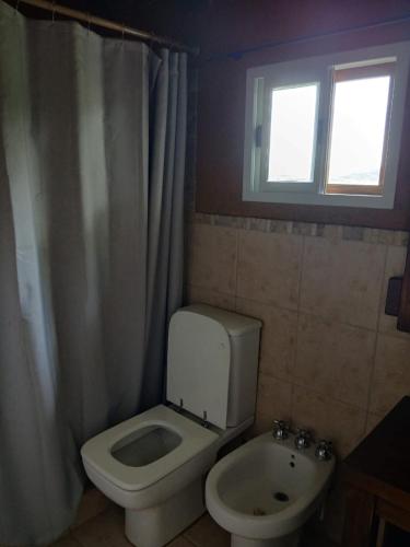 a bathroom with a toilet and a sink and a window at Cabaña Kokopelli in Villa Giardino