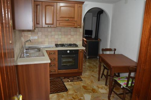 uma cozinha com um lavatório, um fogão e uma mesa em Agriturismo Ghirlanda Norma Rita em Carrodano Inferiore