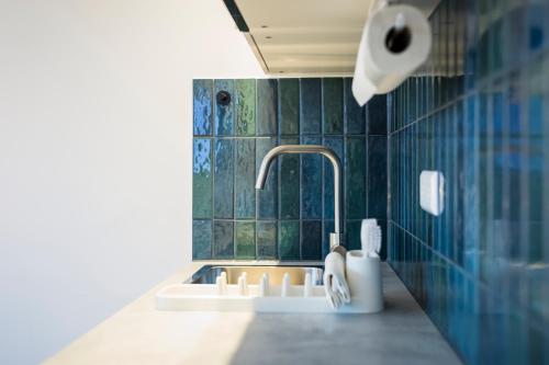 a bathroom with a sink and green tiled walls at Montelio Living in Ettlingen