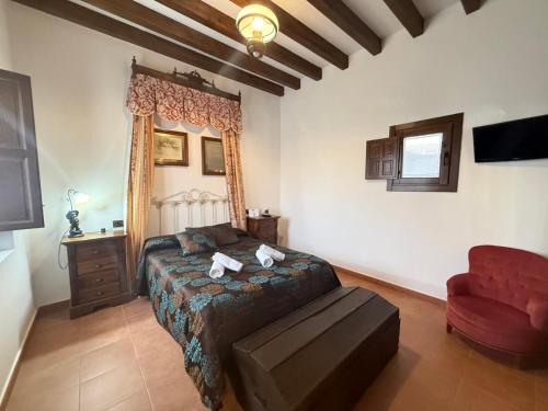 a bedroom with a bed and a red chair at La Casa de la botica -Casa Rural El Romeral de Toledo in Romeral