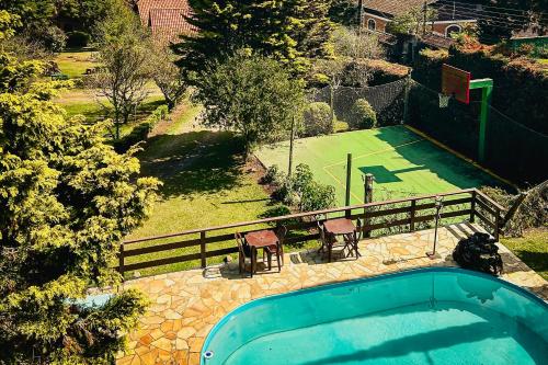 a pool with a table and chairs and a tennis court at VELINN Pousada Locanda Belvedere in Monte Verde