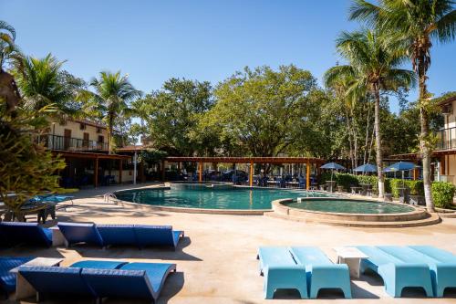a swimming pool with blue lounge chairs and palm trees at Pousada Ilha Vitoria in Ubatuba