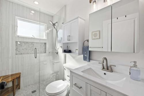 a white bathroom with a toilet and a sink at Luxury 1BR Suite Kitchen, Fireplace, Laundry, BBQ in Simi Valley