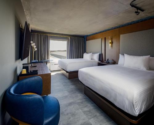 a hotel room with two beds and a blue chair at Bally's Baton Rouge Hotel in Baton Rouge
