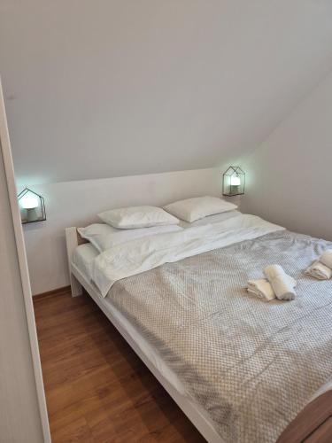 a white bed with two white towels on it at Tündérkert Tündérfészek Vendégház in Sződliget