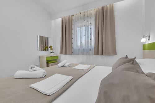 a white bedroom with a bed and a mirror at Apartmani Podest II in Baška Voda