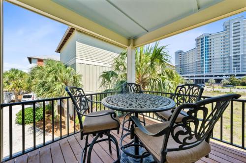 a porch with a table and chairs on a balcony at Lil Js Getaway at Romeo Beach #3 by Youngs Suncoast in Gulf Shores