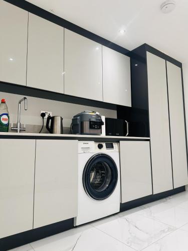 a washing machine in a kitchen with white cabinets at Large Double Bed En-suite Room 20 mins from Heathrow in Burnham