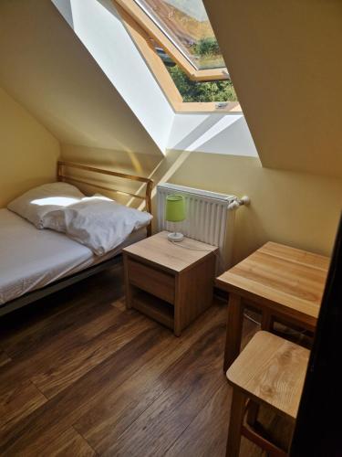 a attic bedroom with a bed and a table at Schronisko Sokoliki in Mysłakowice