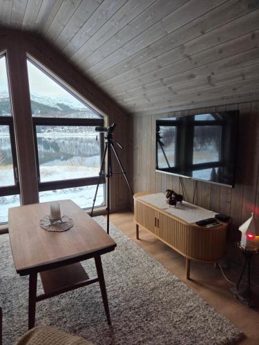 a room with a bed and a table in a room with windows at Harteigen cabin Lofoten retreat in Vestvågøya