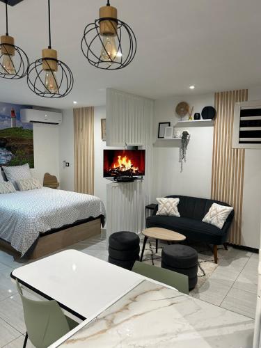 a bedroom with a bed and a living room with a fireplace at Obonheur avec Jacuzzi in Le Gosier