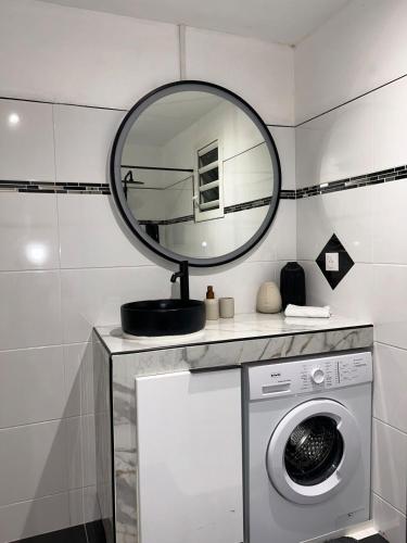a bathroom with a washing machine and a mirror at Obonheur avec Jacuzzi in Le Gosier