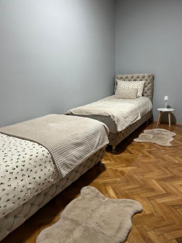 two beds in a room with a wooden floor at MONA app Apatin in Apatin