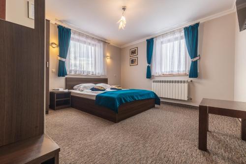 a bedroom with a bed and blue curtains at Ostrysz in Dzianisz
